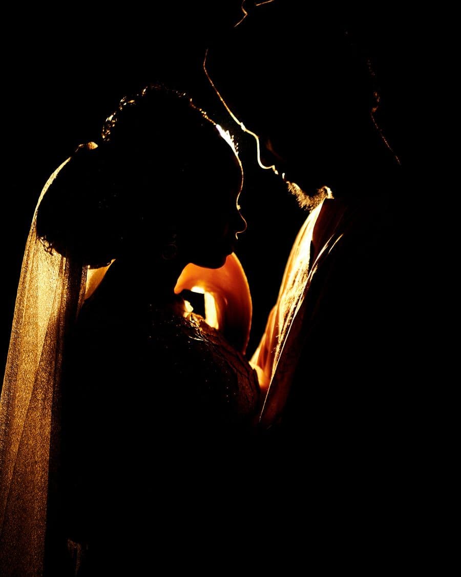 Silhouette of a bride and groom embracing in dramatic light